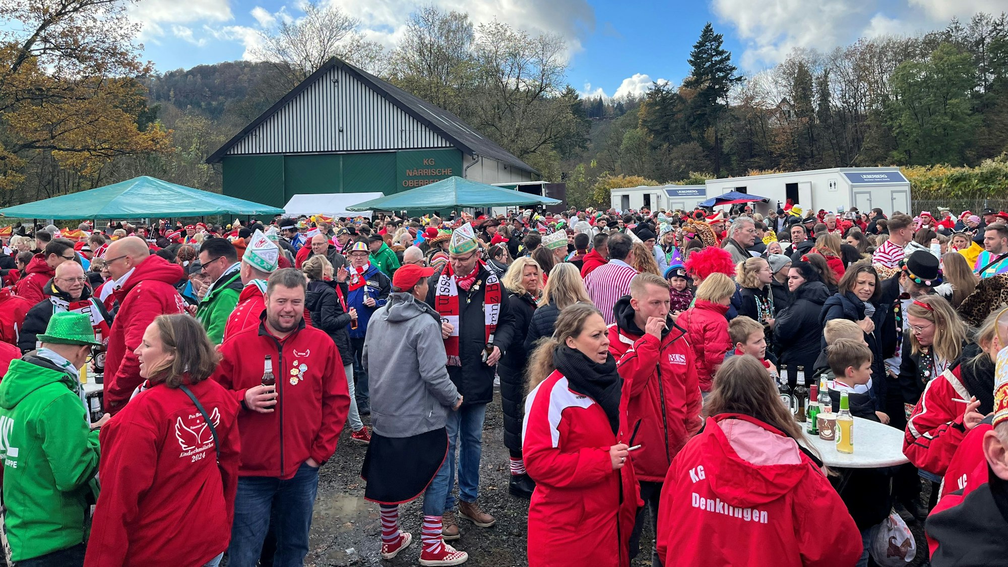 Zahlreiche verkleidete Jecke stehen auf einem Festplatz.