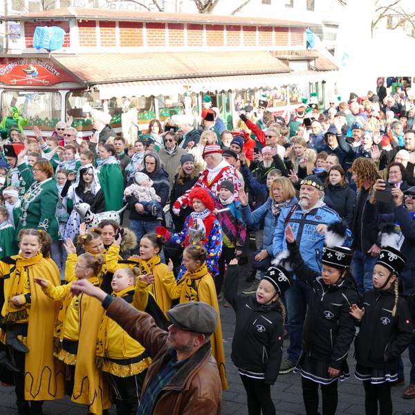 Kinder und Erwachsene stehen in einer großen Menge auf dem Siegburger Markt. Sie tragen Uniformen ihrer Karnevalsgesellschaften in vielen Farben.