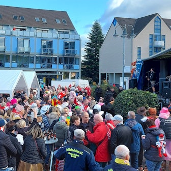 Viele bunt kostümierte Menschen stehen zum Karnevalsauftakt in Mechernich vor einer Bühne.