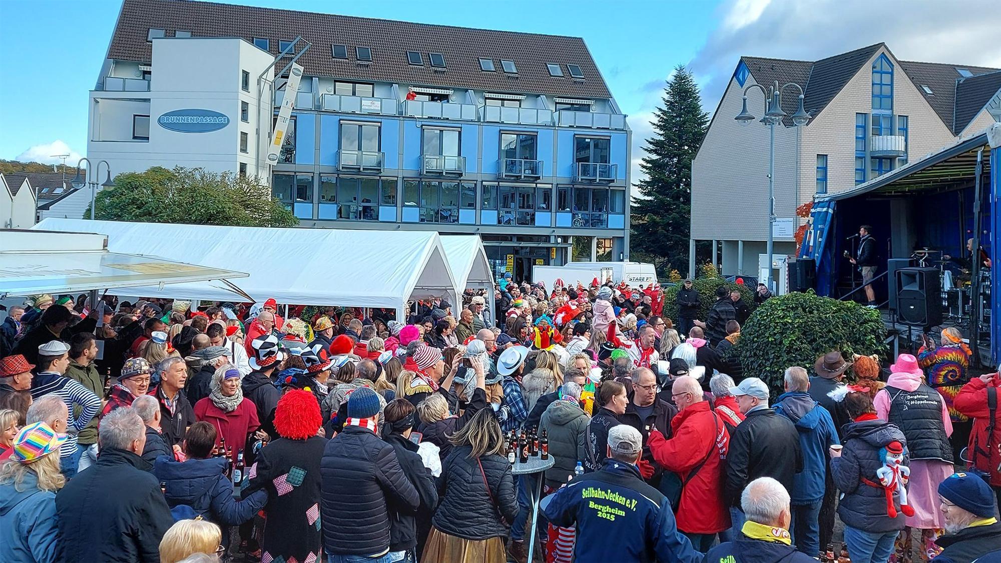 Viele bunt kostümierte Menschen stehen zum Karnevalsauftakt in Mechernich vor einer Bühne.