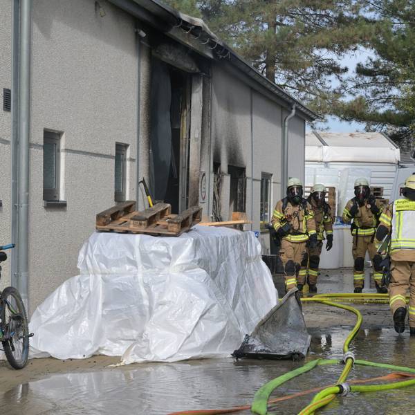 Feuerwehrleute gehen unter Atemschutz über das Firmengelände,