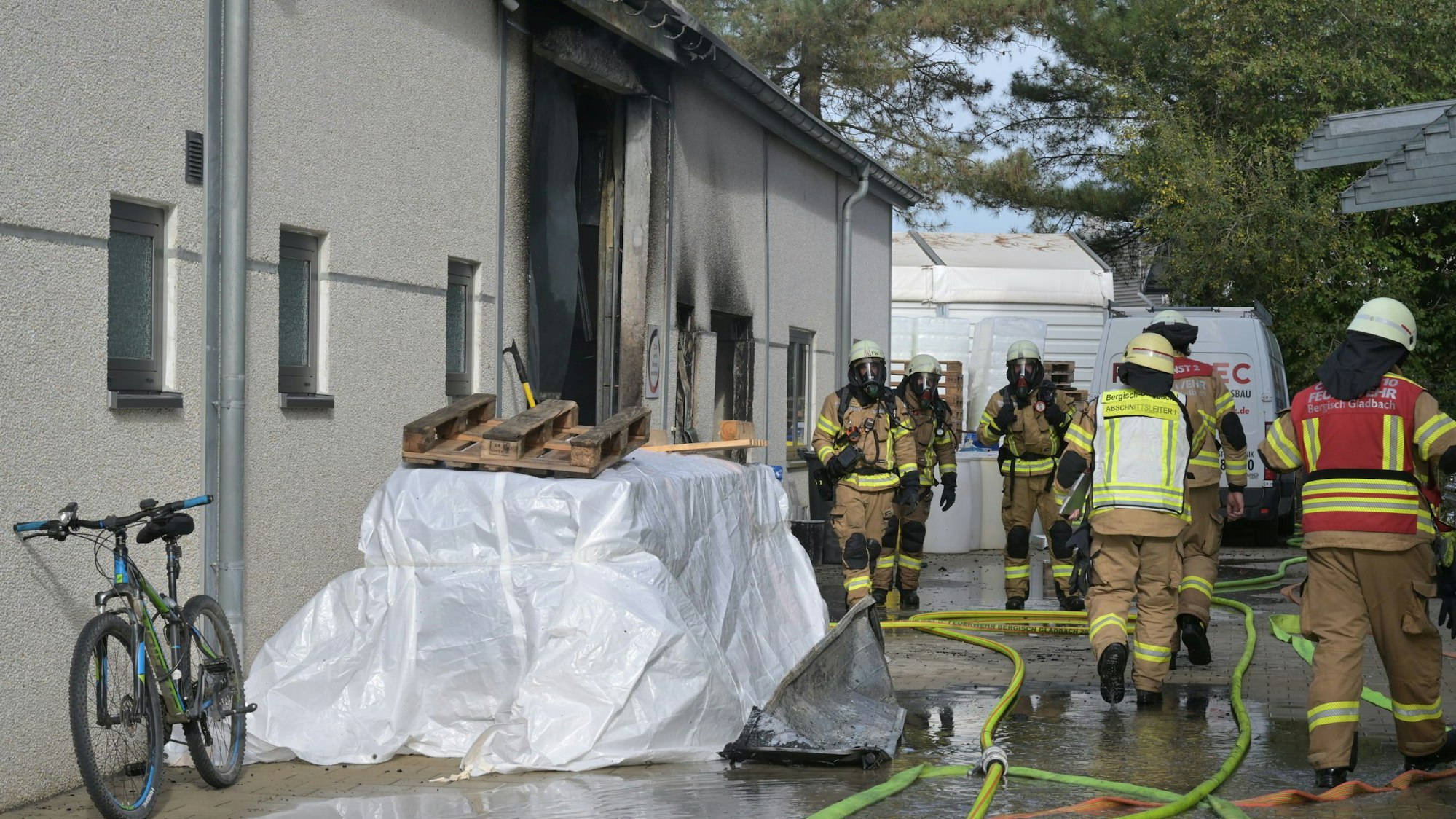Feuerwehrleute gehen unter Atemschutz über das Firmengelände,