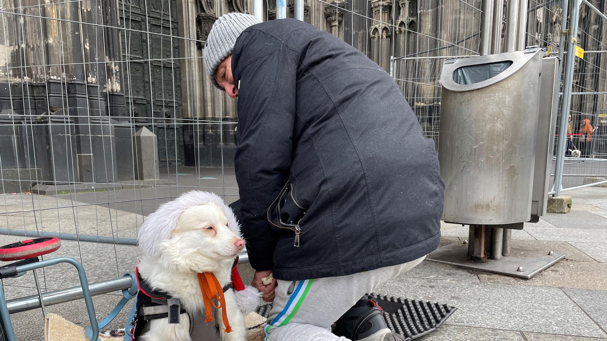 Thomas sitzt mit seinem Hund vor dem Dom.