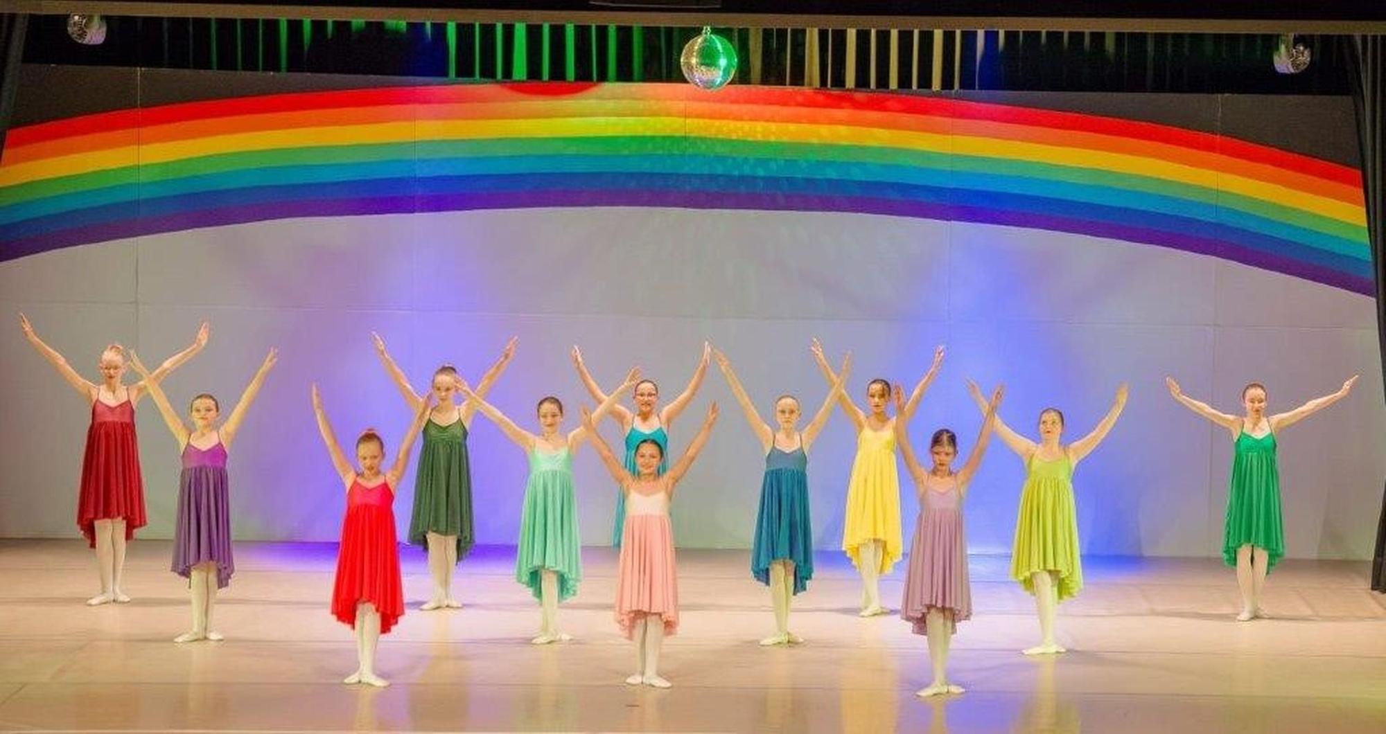 Das Bild zeigt eine Szene aus dem Theater. Zwölf Tänzerinnen stehen auf der Bühne.