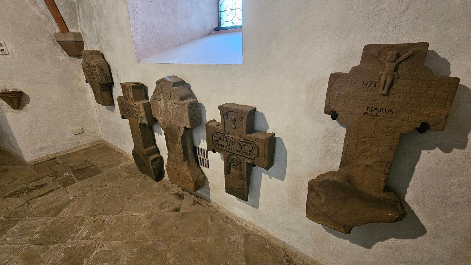 Alte Steinkreuze hängen an einer Wand des Turms.