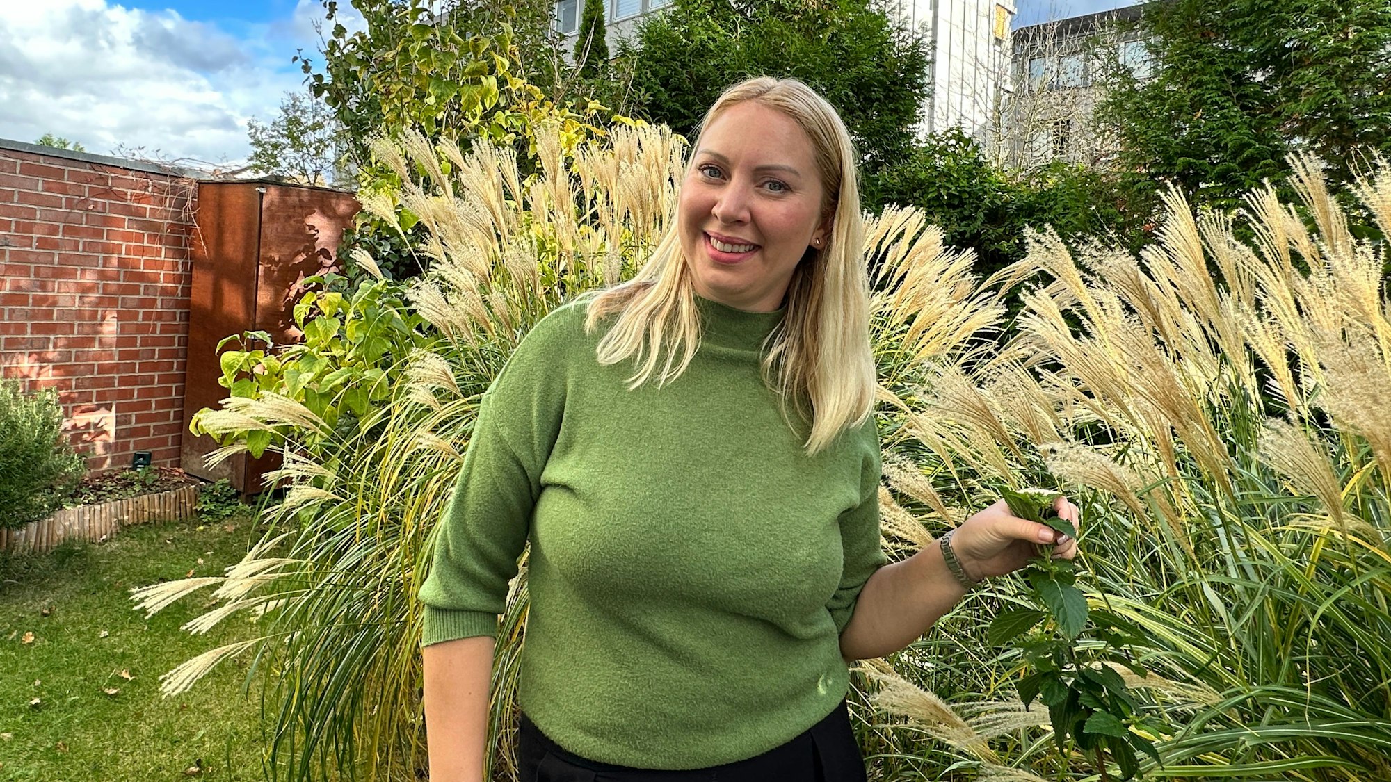 Eine junge Frau steht im Garten.