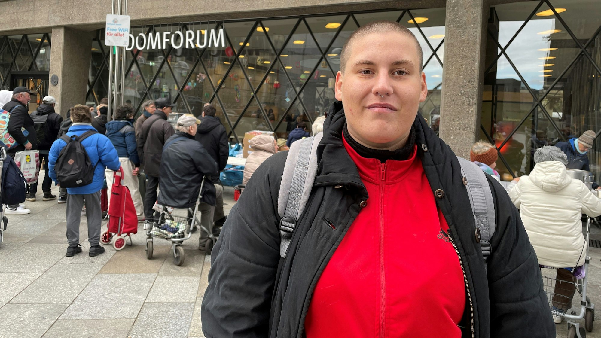 Laura steht mit Rucksack vor der Suppenausgabe.