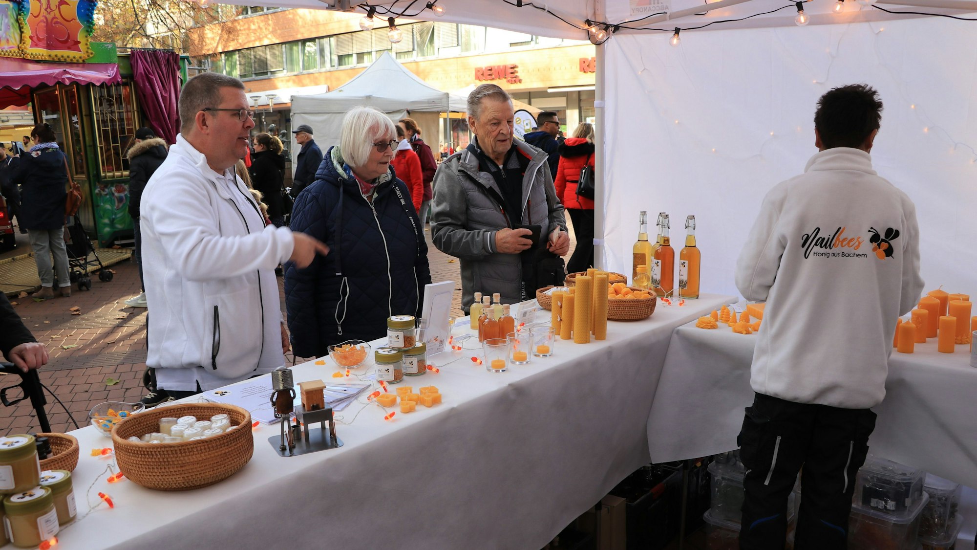 Menschen stehen an einem Stand mit Produkten aus Bienenwachs.