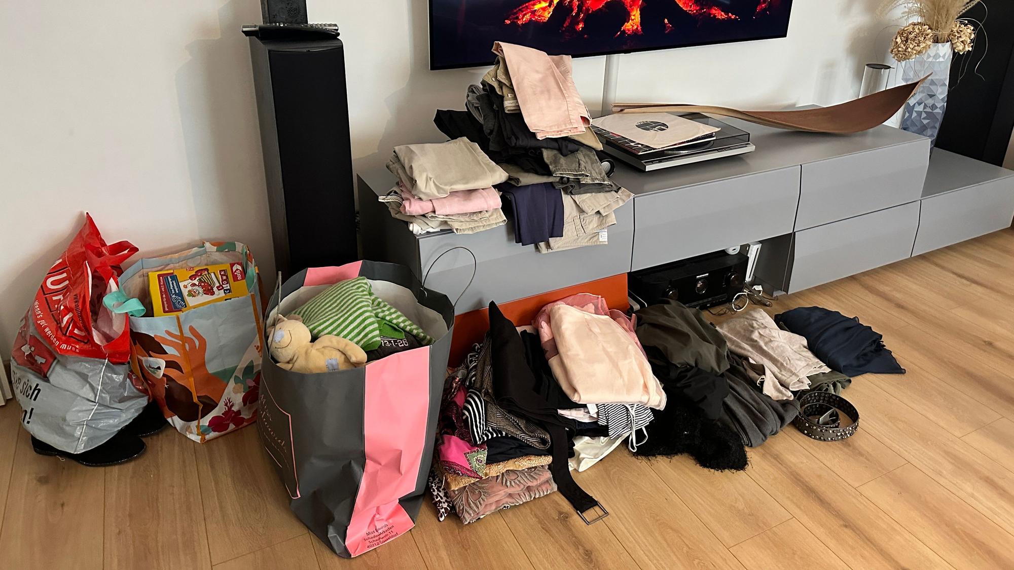 Kleidung in Tüten in einem Wohnzimmer.