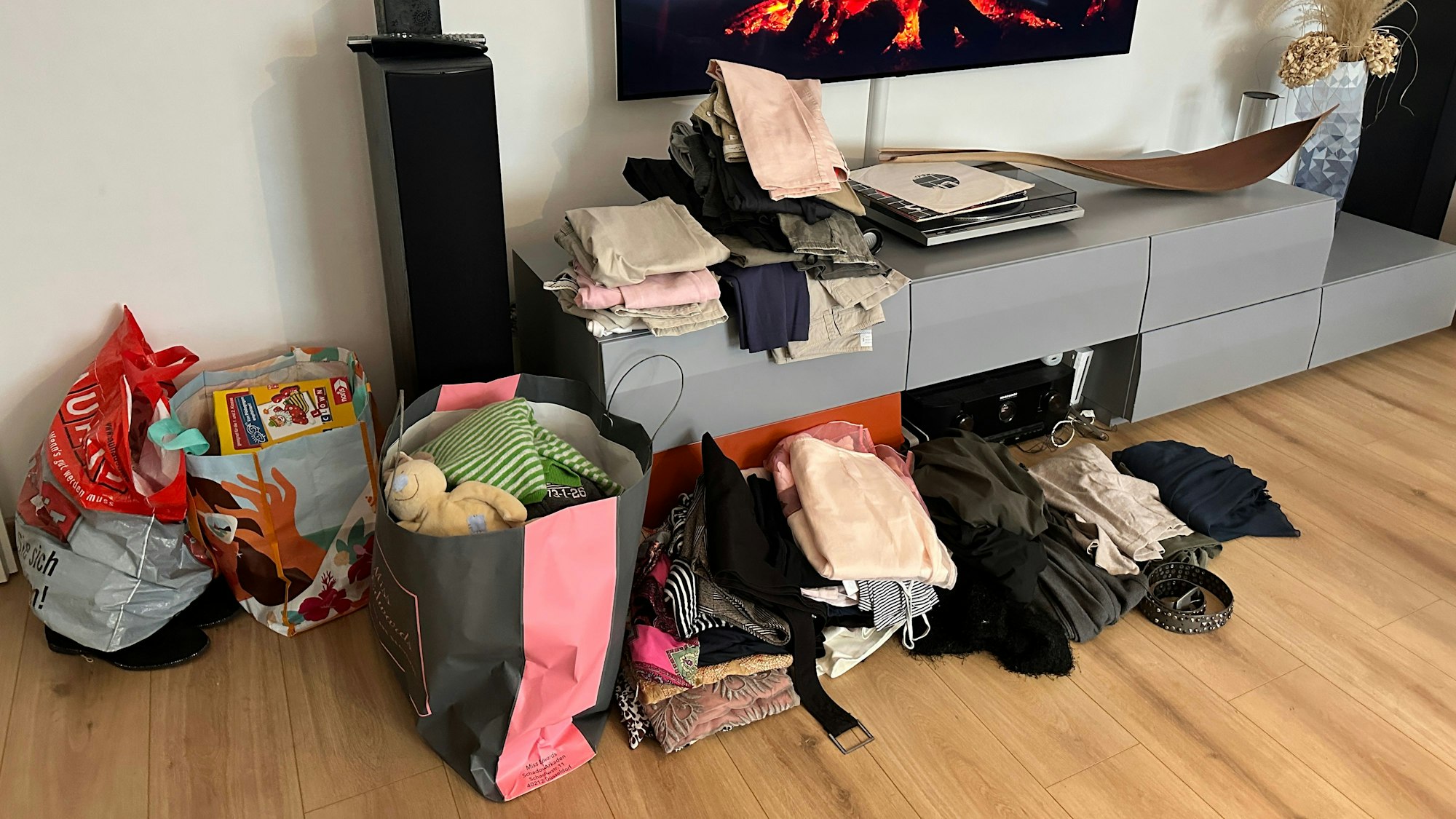 Kleidung in Tüten in einem Wohnzimmer.
