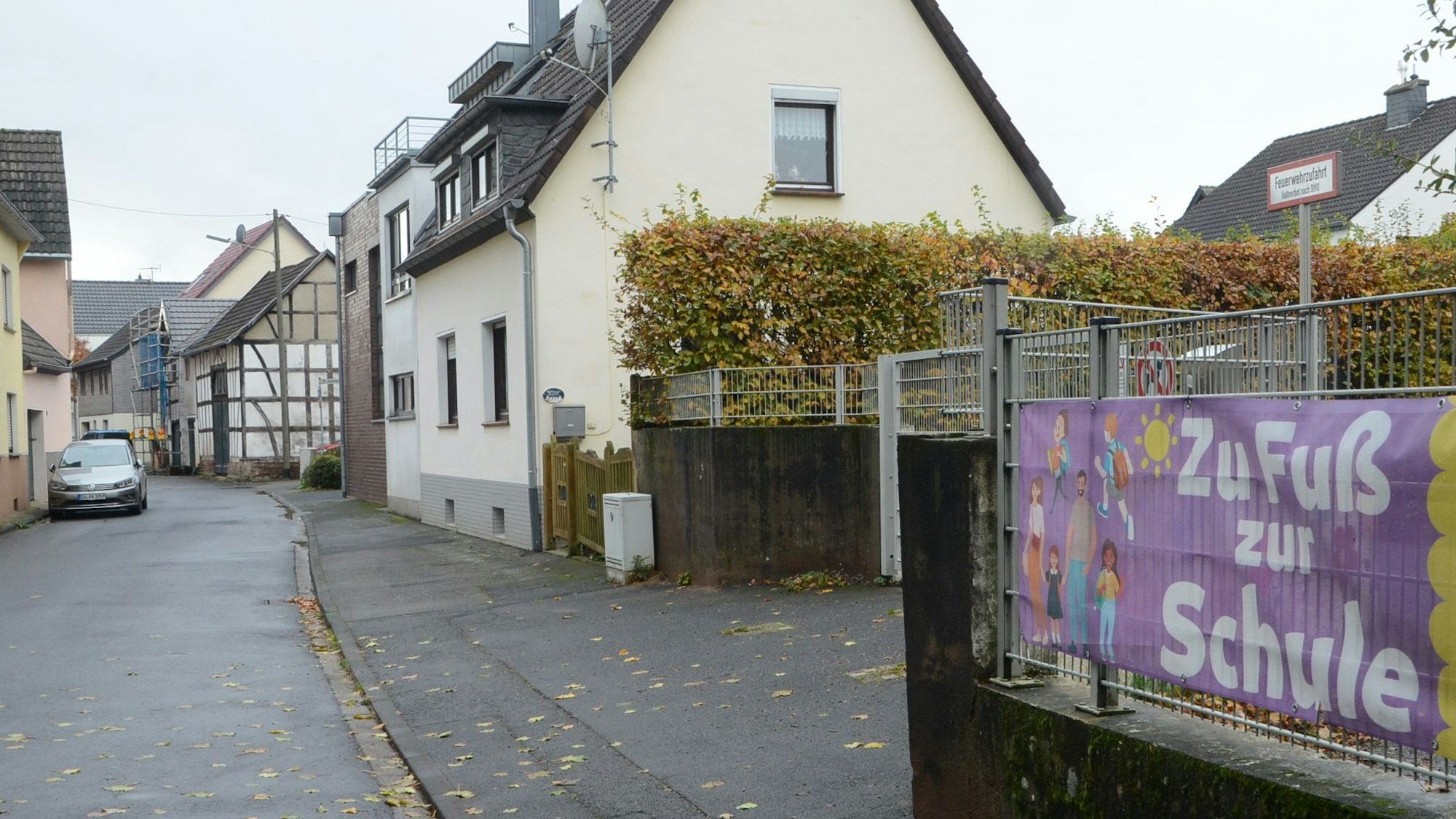 Eine Straße in Müllekoven am Zugang zu einem Schulhof. „Zu Fuß zur Schule“, wirbt ein Transparent am Zaun.