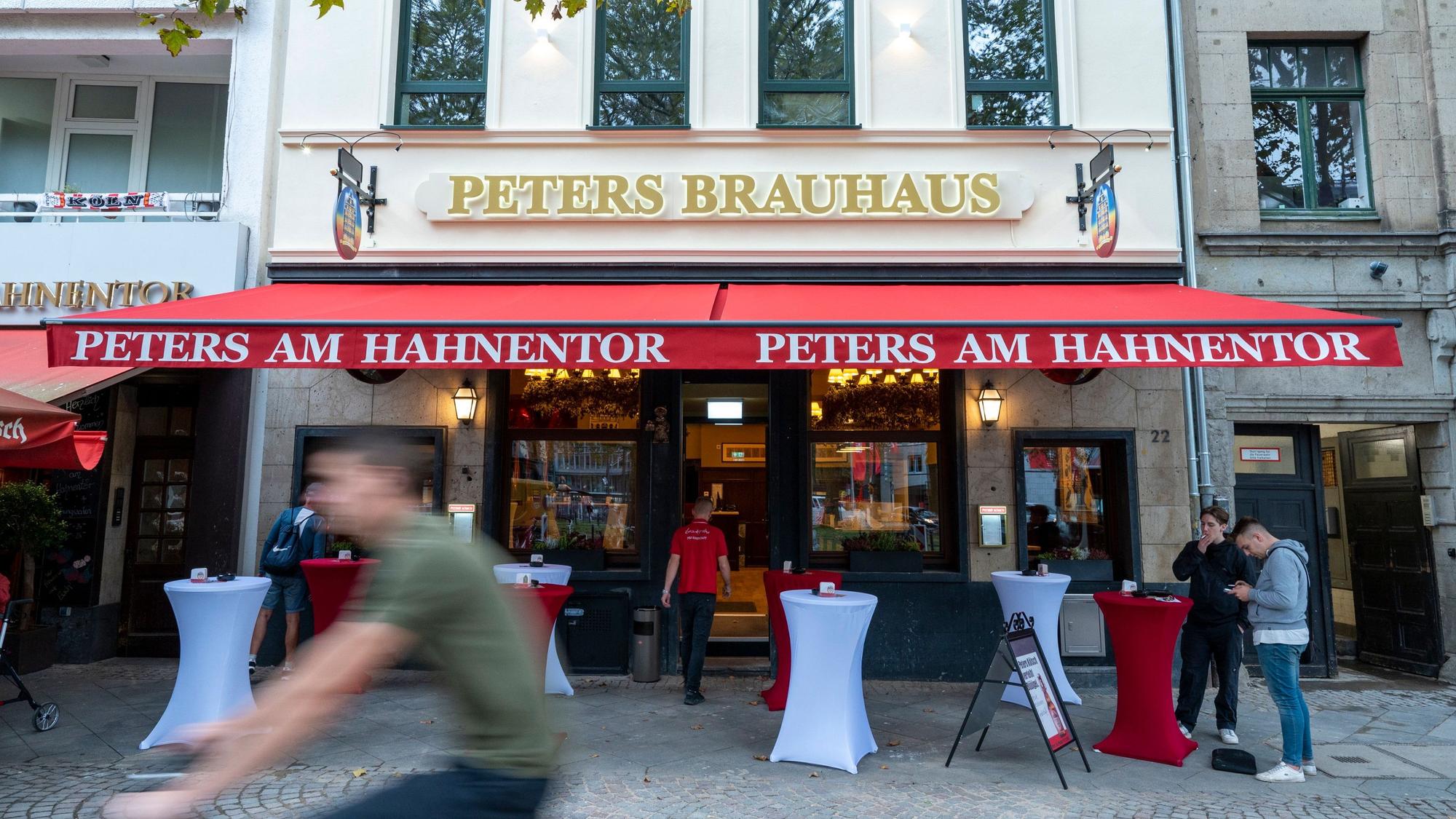 Das Peters Brauhaus mit roten und weißen Tischen draußen.