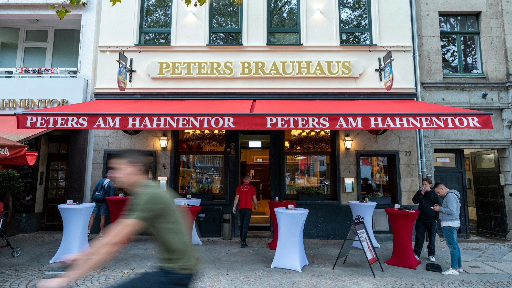 Das Peters Brauhaus mit roten und weißen Tischen draußen.