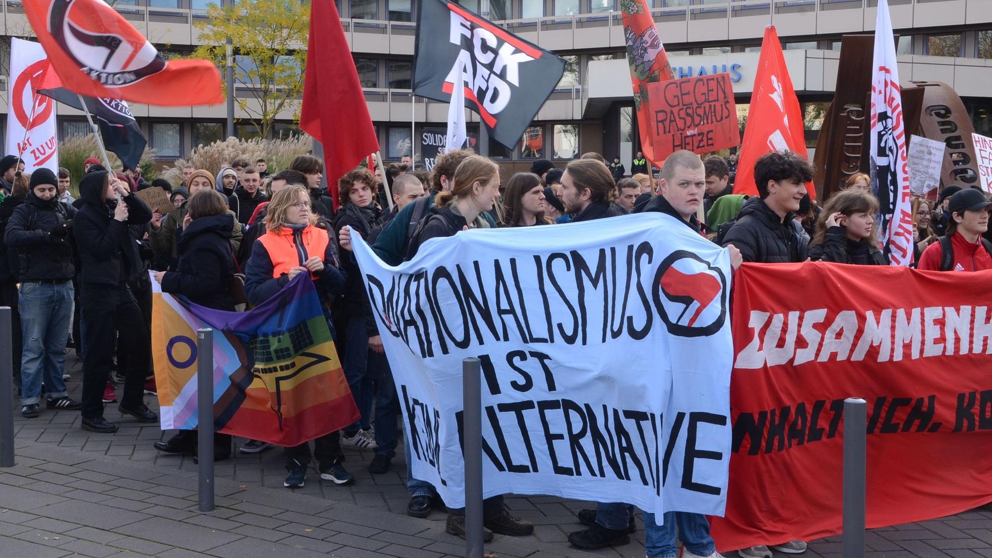 Menschen mit Spruchbändern und Fahnen auf der Straße vor dem Troisdorfer Rathaus.