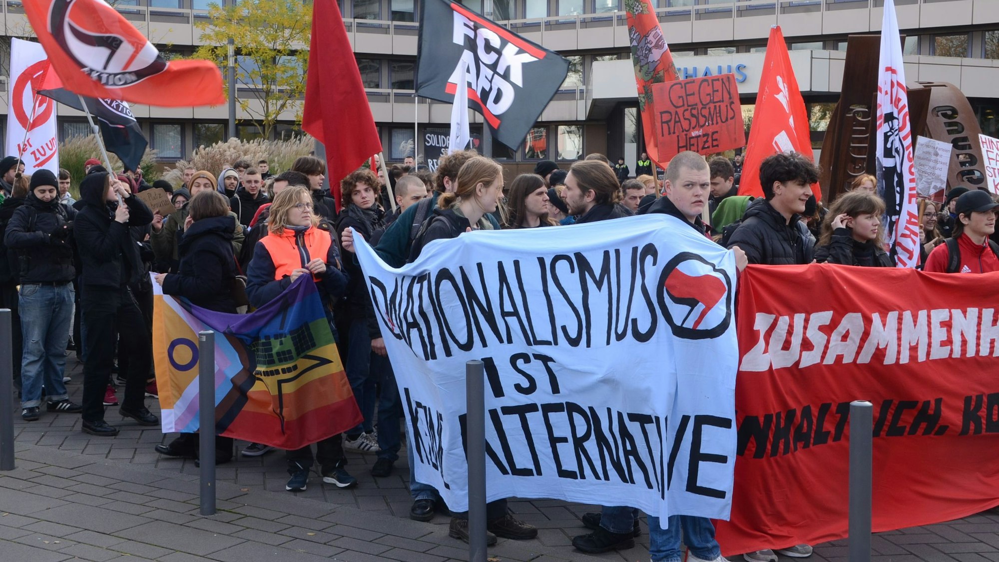 Menschen mit Spruchbändern und Fahnen auf der Straße vor dem Troisdorfer Rathaus.