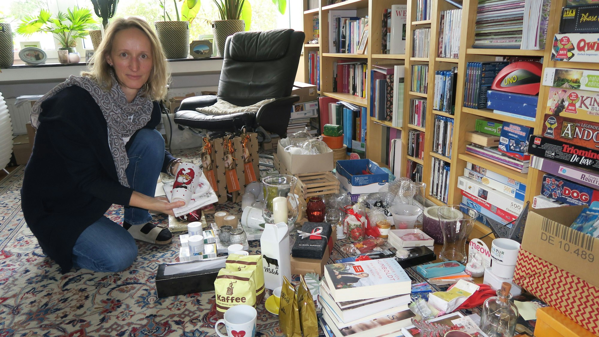Eine Frau sortiert in ihrem Wohnzimmer Ware für den Basar.