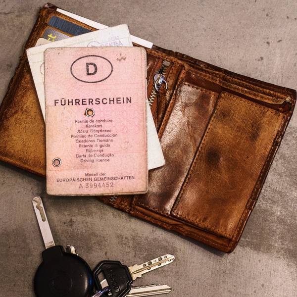 Ein „rosa Führerschein“, ein Autoschlüssel, eine Geldbörse und ein Fahrzeugschein liegen auf dem Tisch