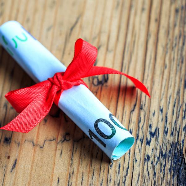 100 Euro Schein eingerollt und mit Schleife als Geschenk verpackt