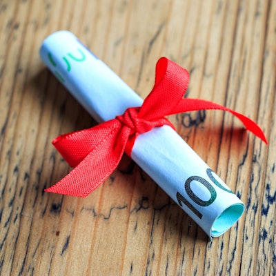 100 Euro Schein eingerollt und mit Schleife als Geschenk verpackt