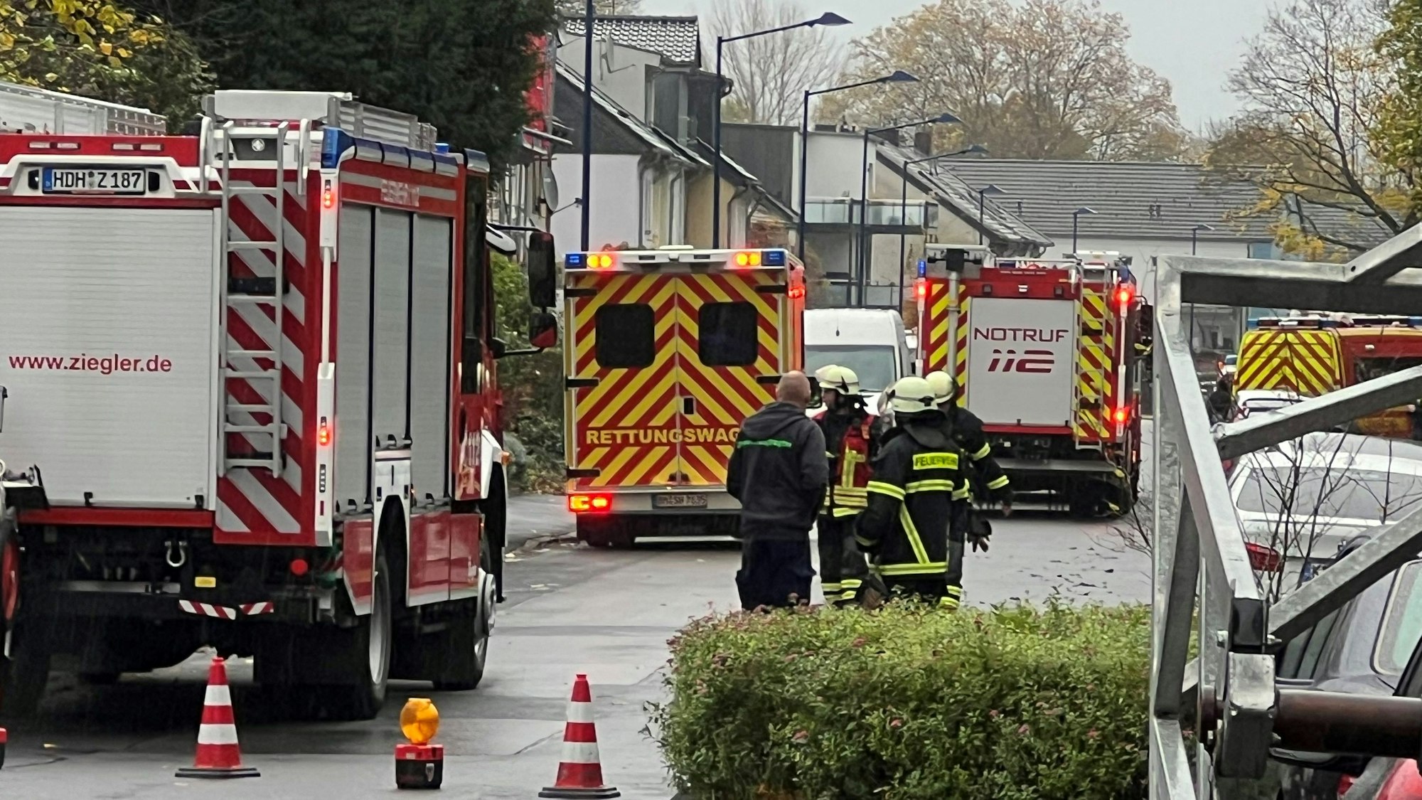 Das Bild zeigt mehrere Einsatzkräfte und mehrere Einsatzfahrzeuge der Feuerwehr auf einer Straße.