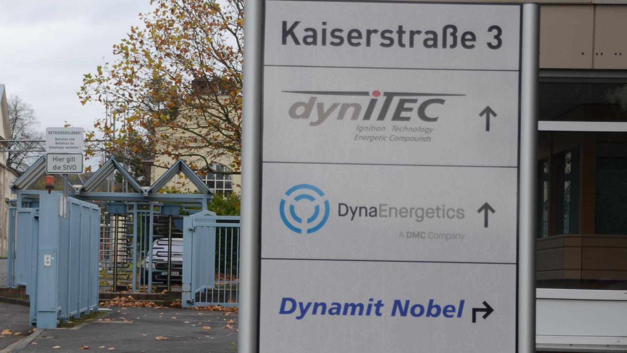 Eine Infotafel mit Firmennamen am Tor zu einem Industriegelände.