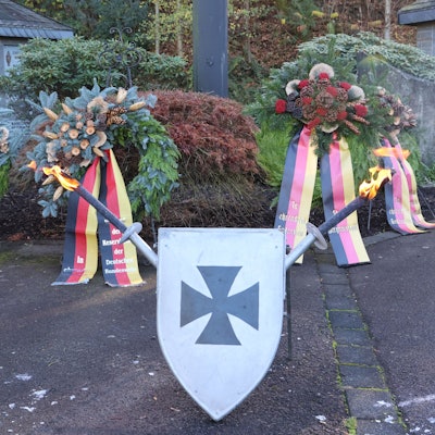 Man sieht ein Schild mit Schwertern und Trauerkränze.
