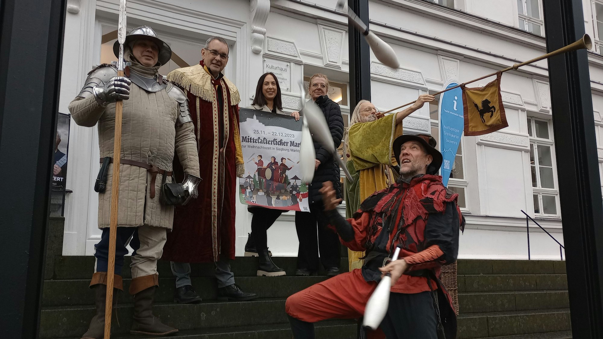 Menschen in mittelalterlichen Kostümen auf einer Rathaustreppe.