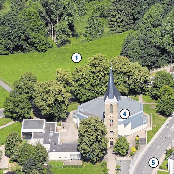 Häuser und eine Kirche stehen an einer Wiese.