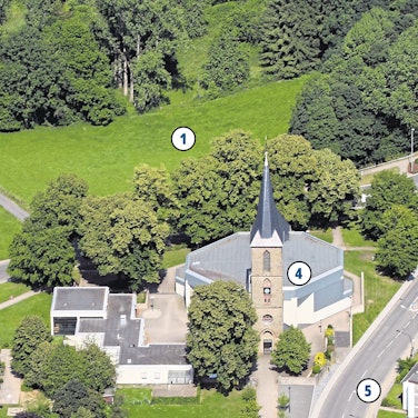 Häuser und eine Kirche stehen an einer Wiese.