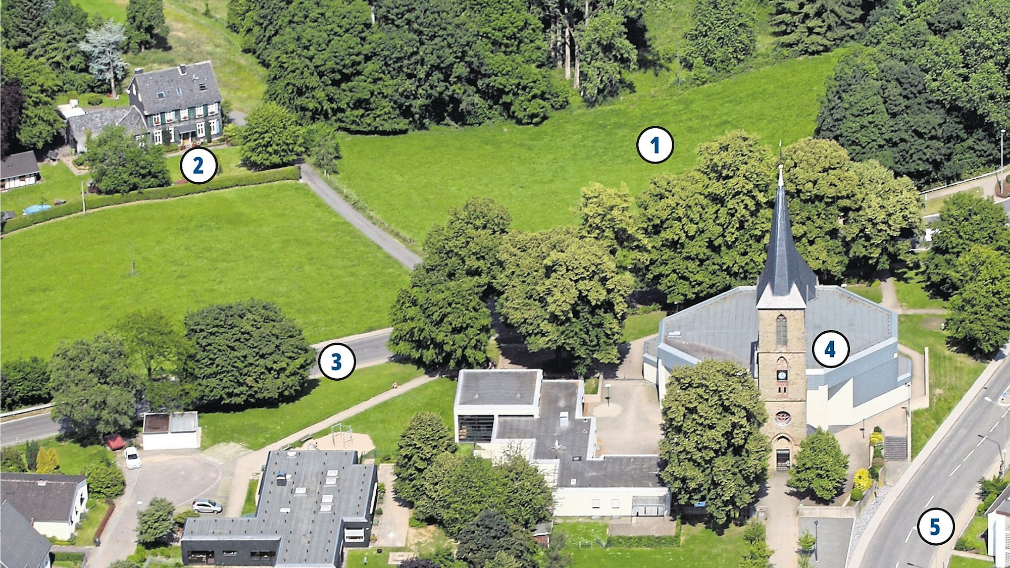 Häuser und eine Kirche stehen an einer Wiese.