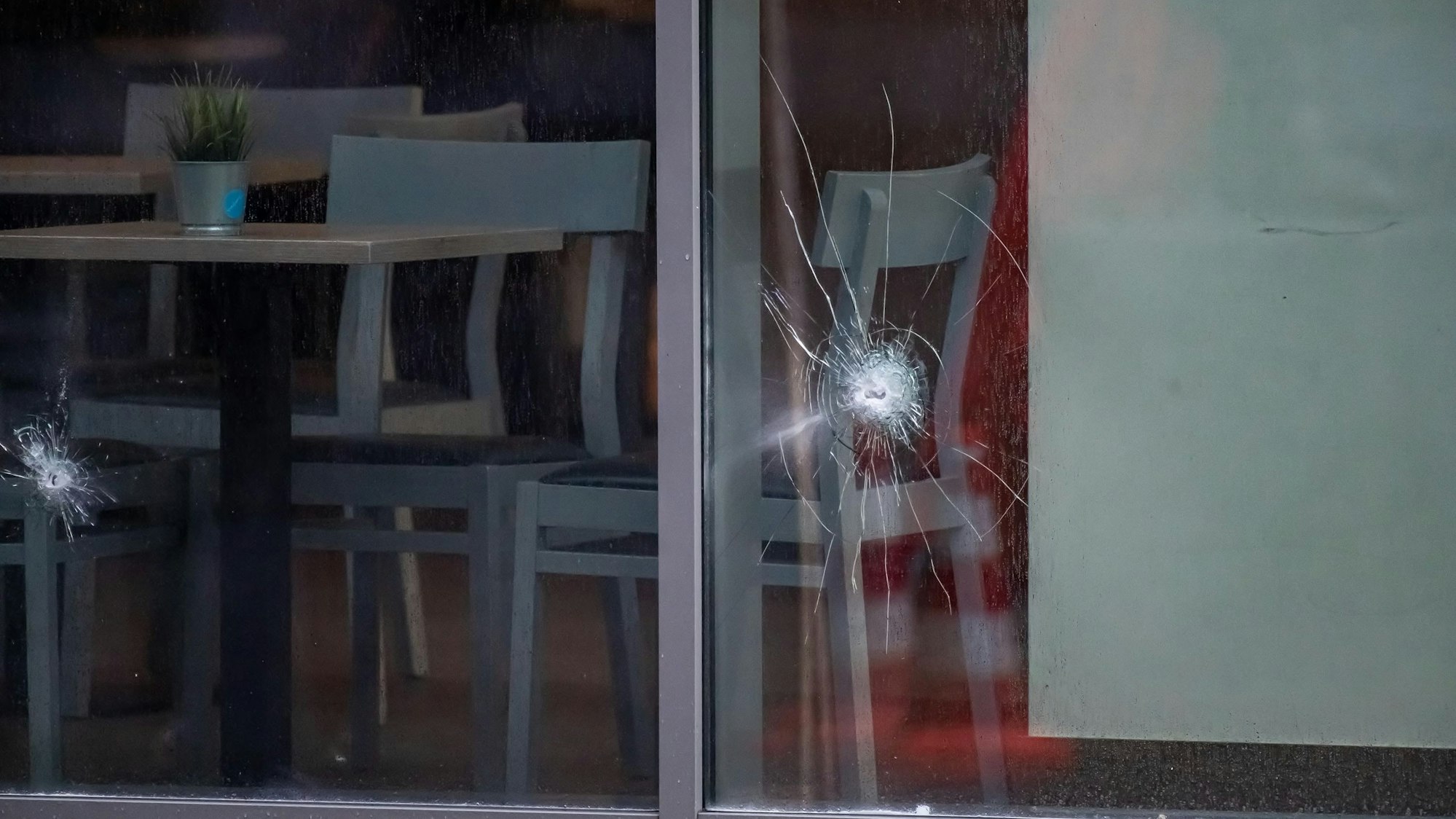 In einer Fensterscheibe des Backgeschäfts sind mehrere Einschusslöcher zu sehen.