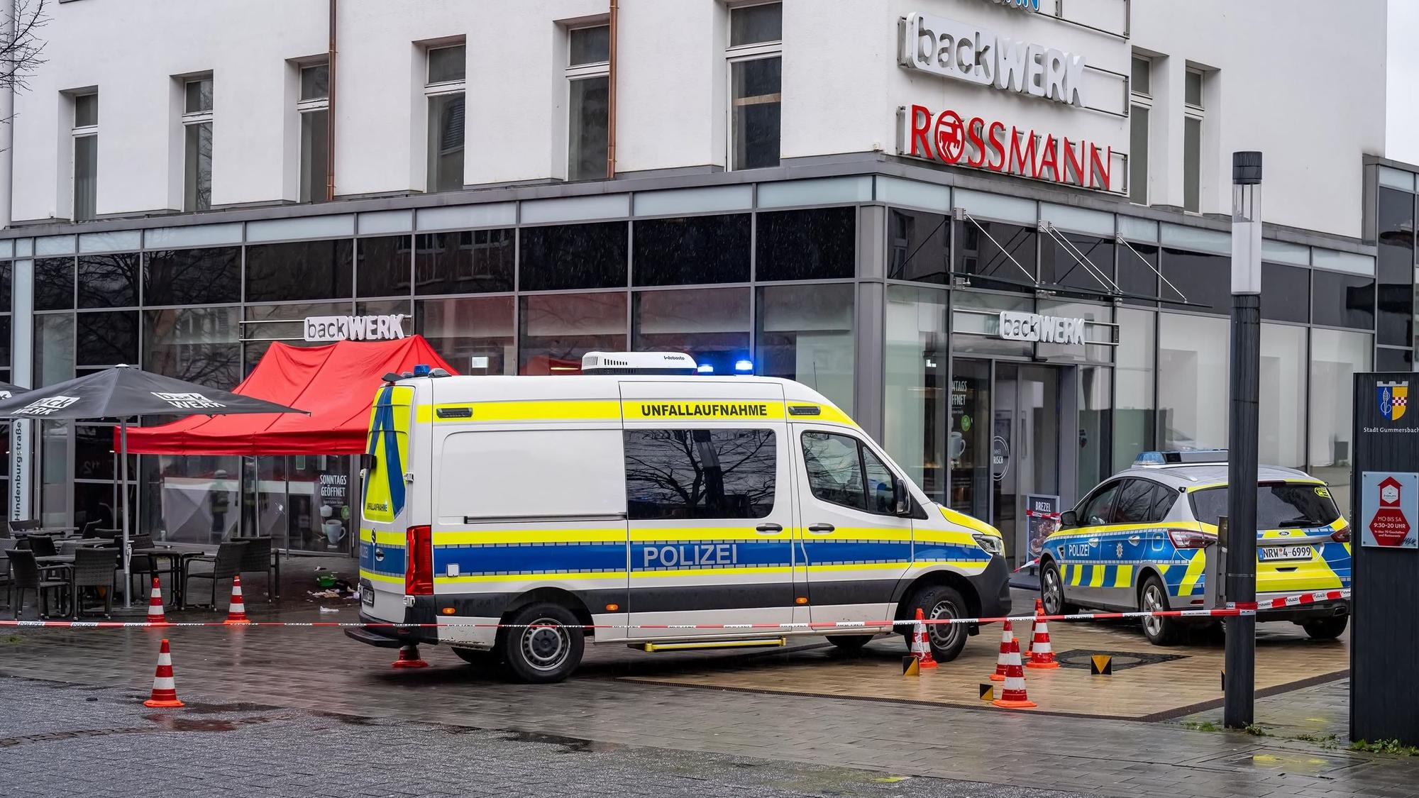 Zwei Polizeiautos stehen vor einem Backgeschäft. Auch Absperrband und ein Pavillon sind zu sehen.