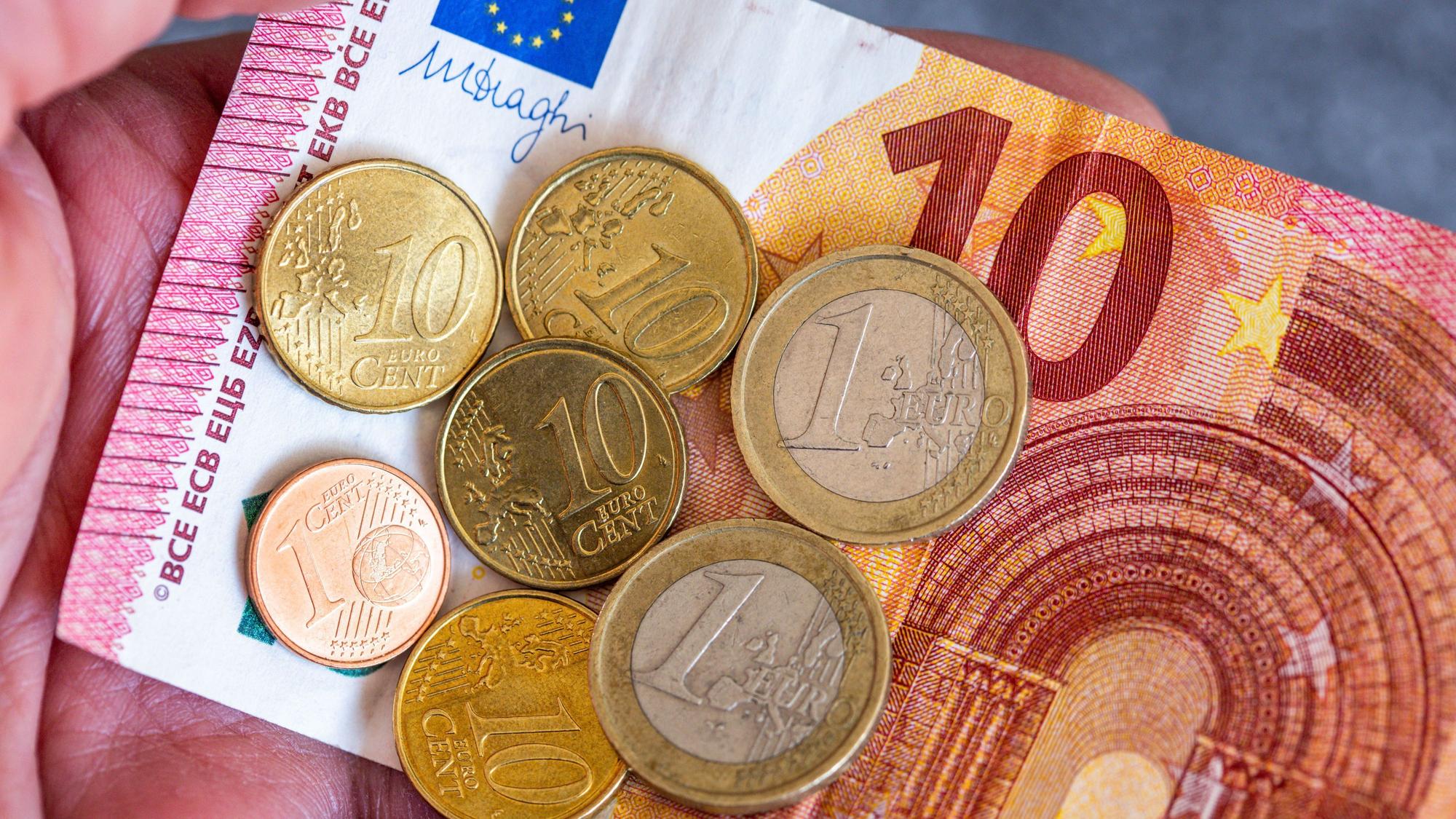 ARCHIV - 26.06.2023, Berlin: Geldscheine und Euromünzen mit dem Wert von 12,41 Euro liegen auf einer Hand.