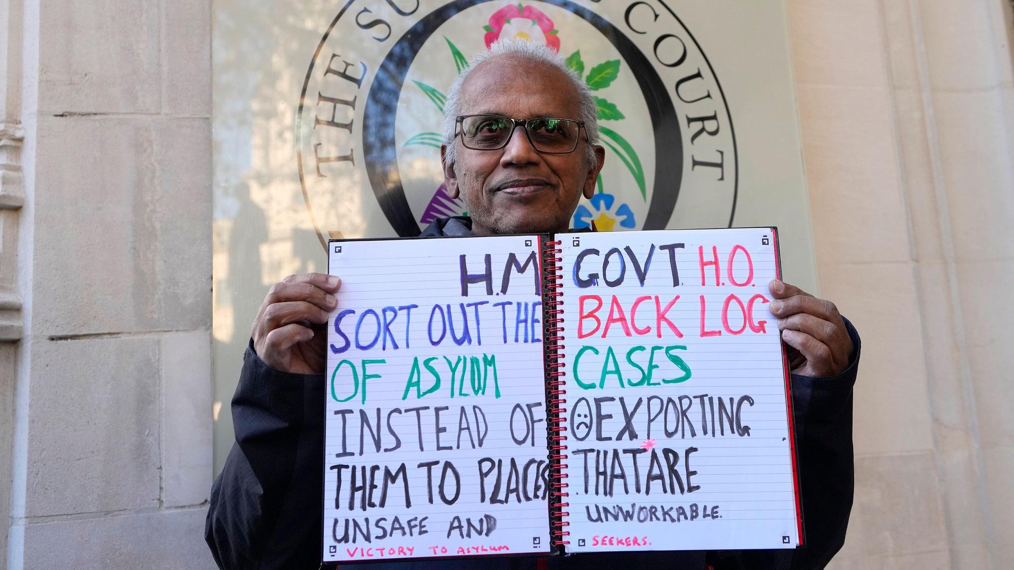 15.11.2023, Großbritannien, London: Ein Demonstrant steht vor dem Obersten Gerichtshof. Die britische Regierung ist vor Gericht mit ihren Plänen gescheitert, Asylbewerber nach Ruanda abzuschieben. Das Oberste Gericht in London nannte das Vorhaben am Mittwoch, 15.11.2023, rechtswidrig. Foto: Kirsty Wigglesworth/AP +++ dpa-Bildfunk +++