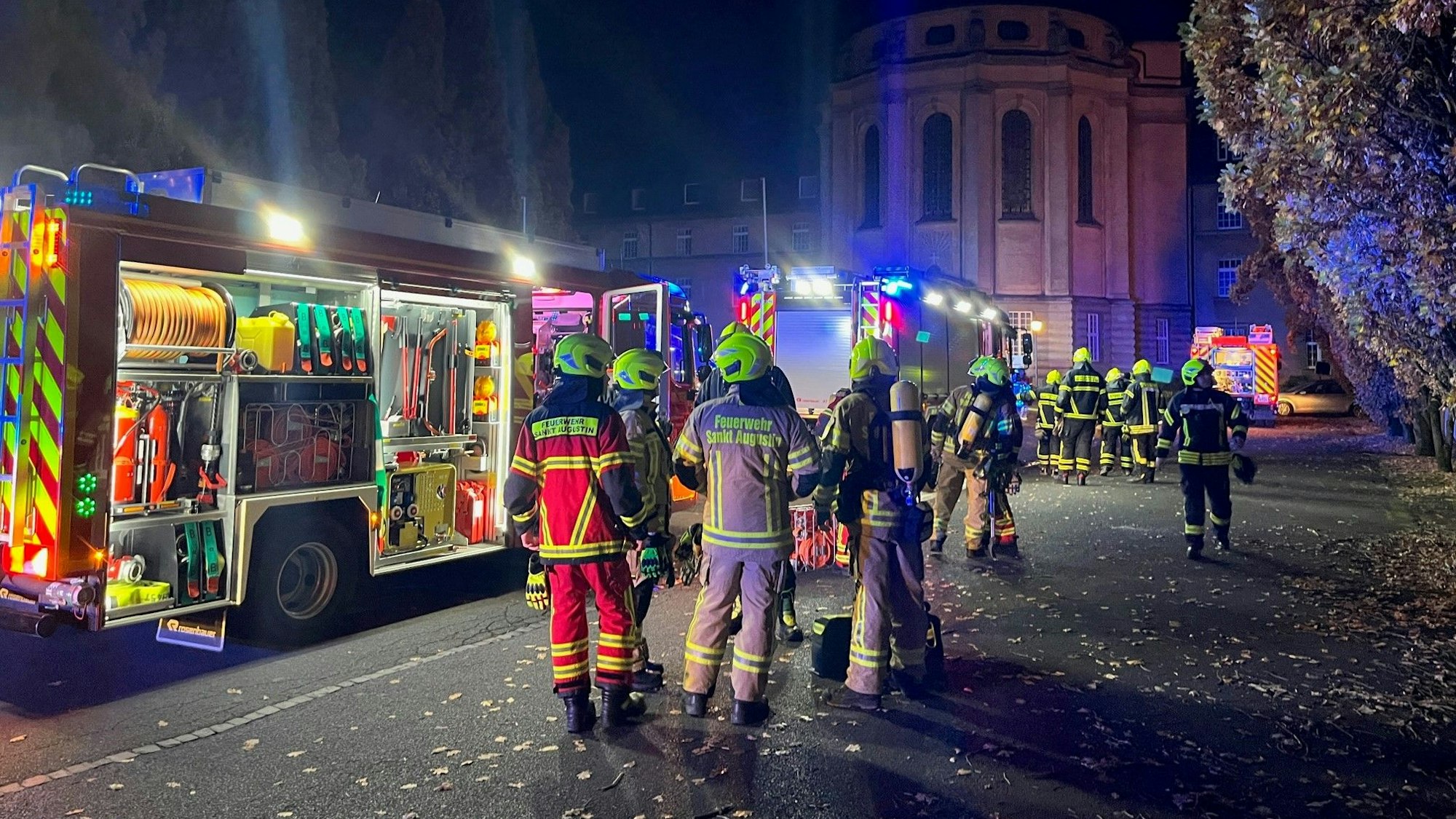 Feuerwehrleute und -fahrzeuge stehen vor einem historischen Gebäude.