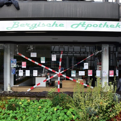Bergische Apotheke in Much. Rotweißes Flatterband ist kreuz und quer vor das Schaufenster gespannt.