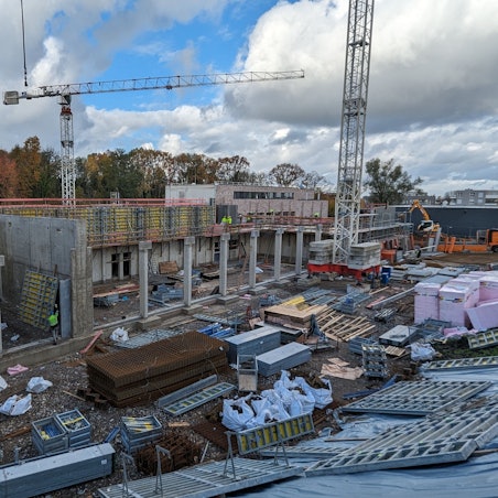Ein Rohbau mit Baurkränen und viel Baumaterial.