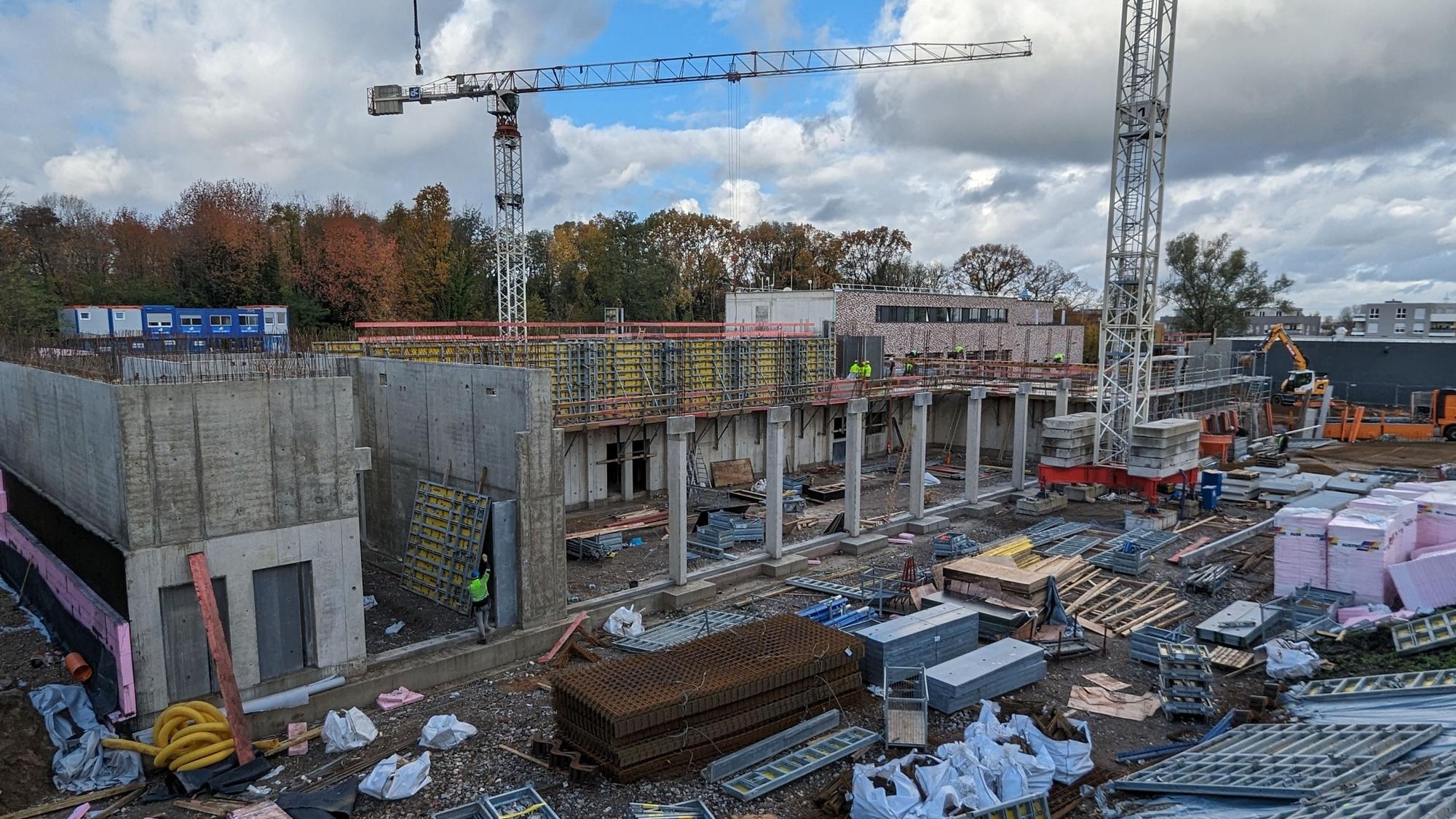 Eine Baustelle mit Rohbau, Baukran und Baumaterialien.