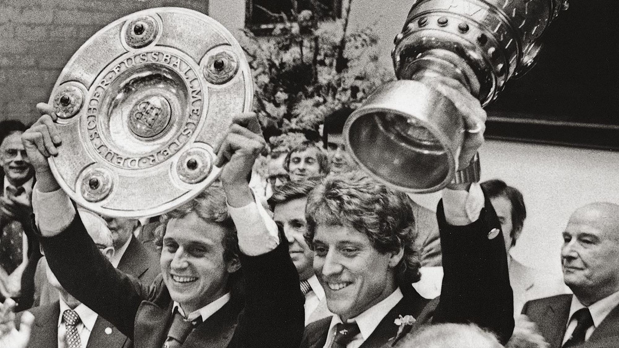 Zwei Männer, die jeweils einen Pokal hochhalten