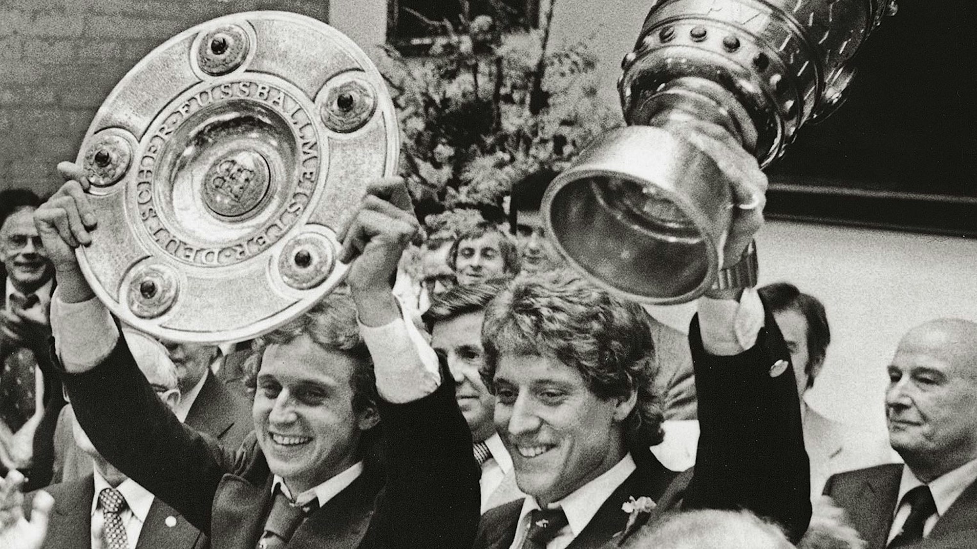 Zwei Männer, die jeweils einen Pokal hochhalten