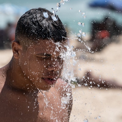 14.11.2023, Brasilien, Rio De Janeiro: Ein Mann duscht am Strand von Ipanema. Brasilien wird derzeit von einer Hitzewelle heimgesucht. Foto: Wang Tiancong/XinHua/dpa +++ dpa-Bildfunk +++