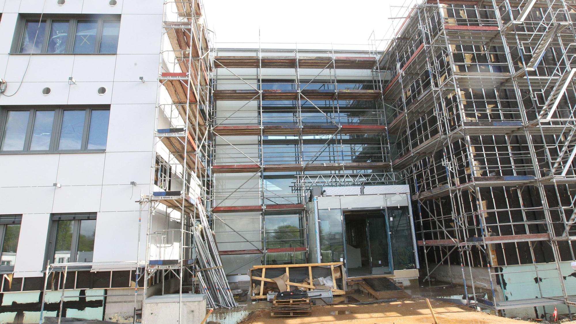 Die Baustelle eines großen Schulgebäudes. Ein Teil ist noch eingerüstet.