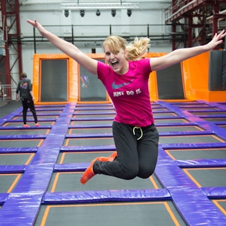Eine Frau springt in Deutschlands größtem Trampolinpark Jump House Berlin auf Trampolinen.