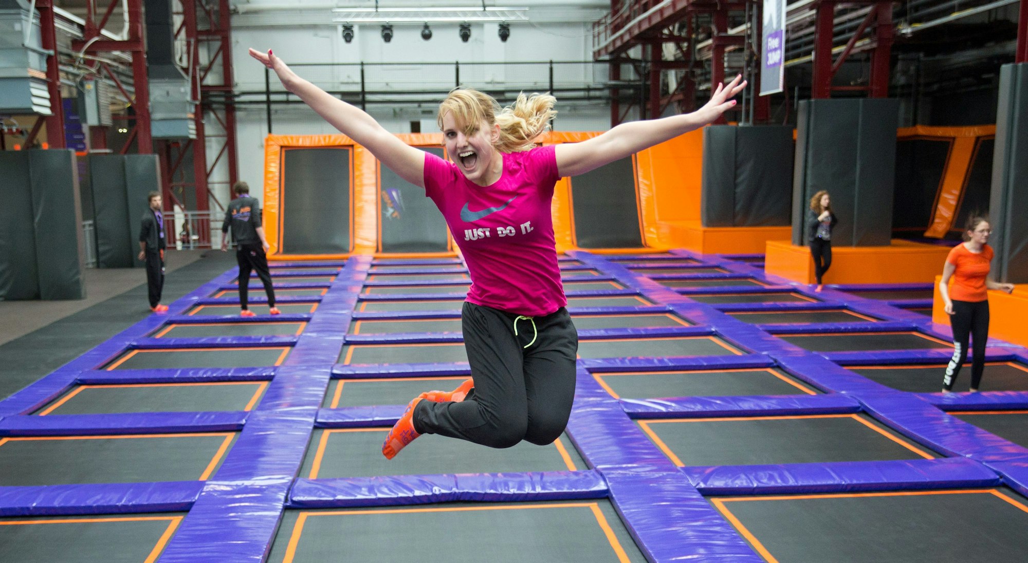 Eine Frau springt in Deutschlands größtem Trampolinpark Jump House Berlin auf Trampolinen.