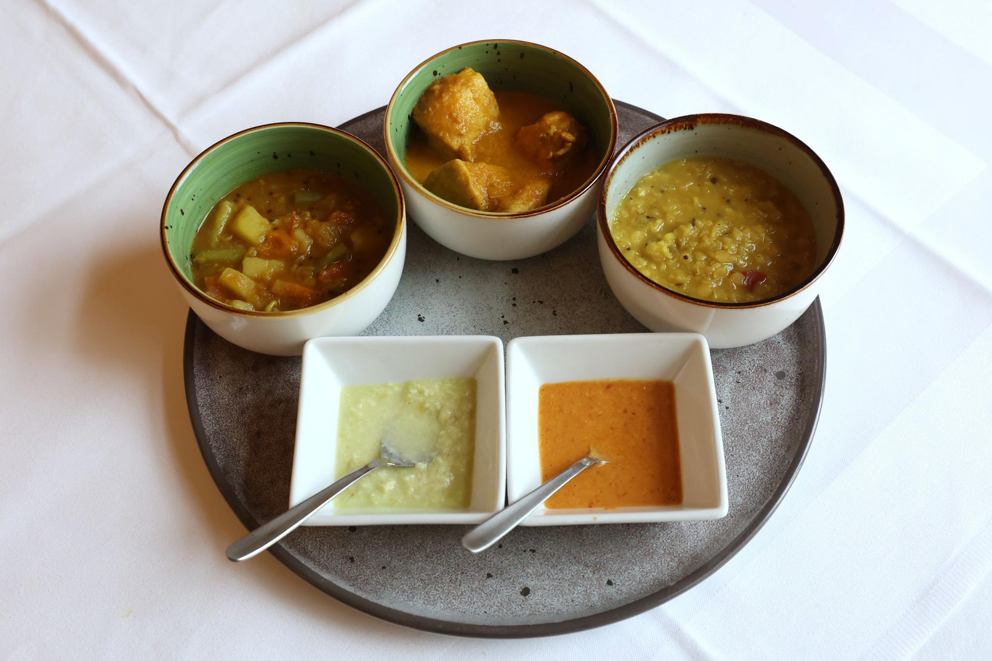 Verschiedene Schälchen mit Curry-Gerichten stehen auf einem Tisch.