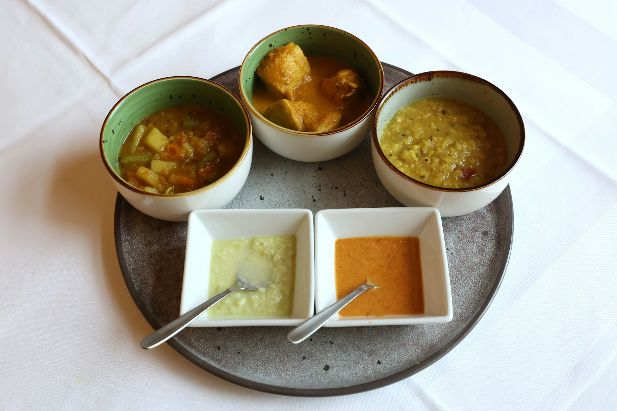 Verschiedene Schälchen mit Curry-Gerichten stehen auf einem Tisch.