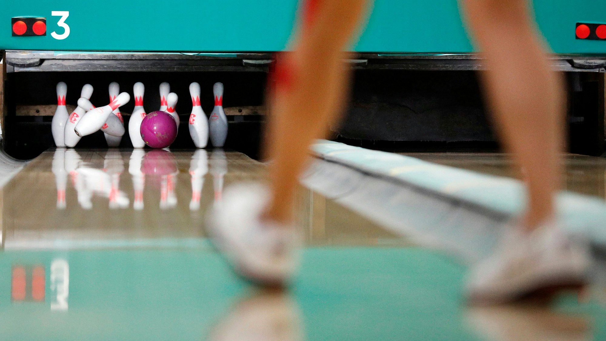 Eine Person geht vor einer Bowling-Bahn.