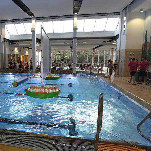 Das Aquarena-Hallenbad in Neunkirchen: Wasser glitzert im Becken, Menschen stehen am Beckenrand.