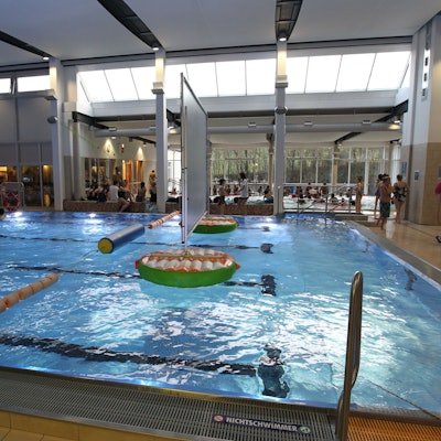 Das Aquarena-Hallenbad in Neunkirchen: Wasser glitzert im Becken, Menschen stehen am Beckenrand.