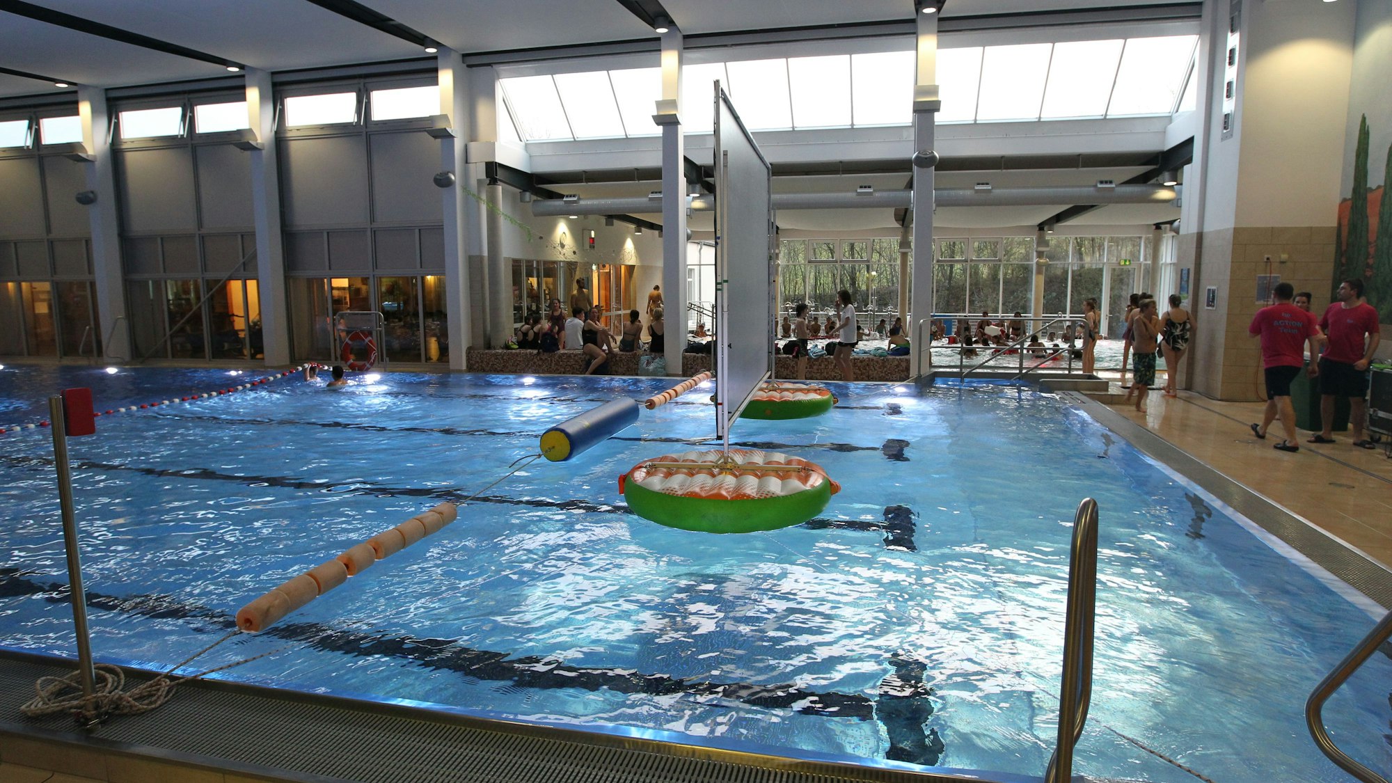 Das Aquarena-Hallenbad in Neunkirchen: Wasser glitzert im Becken, Menschen stehen am Beckenrand.